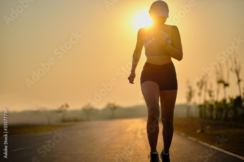 Young women runner run on the road during sun rise