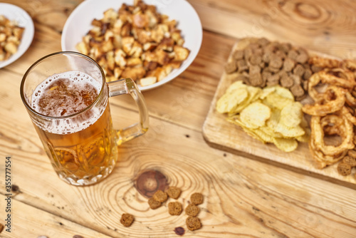 A glass of beer and different snacks on the table. Celebrating international beer day or Octoberfest. Drinking beer after a hard working day or week