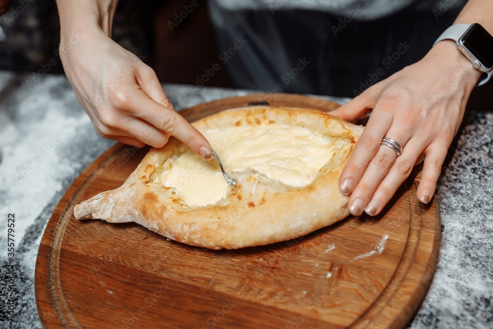 Chef cooking khachapuri with cheese and egg. Georgian national cuisine