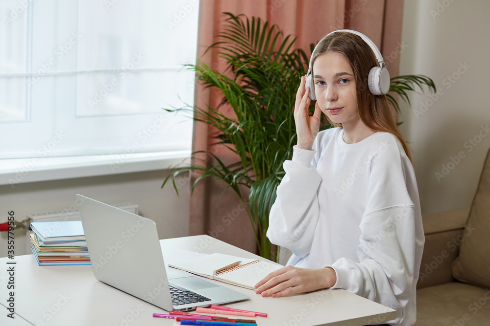 A cute girl is sitting on the couch and is studying online with headphones. A cute girl is sitting on the couch and is studying online with headphones.