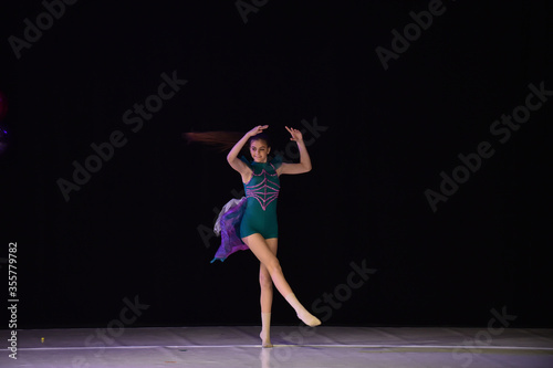 Young teenage girl performing modern dance on stage