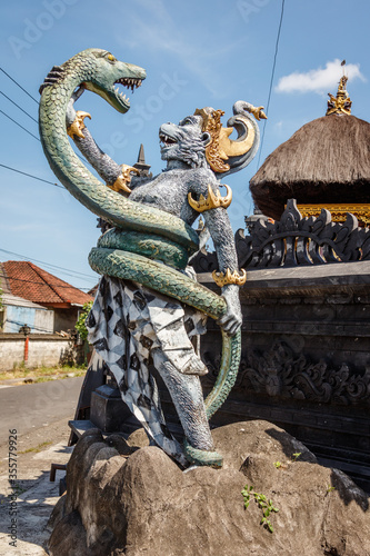 Statue of Hanuman, Hindu god and divine monkey (vanara) companion of the god Rama, fighting naga (snake). Bali, Indonesia. Vertical image. photo