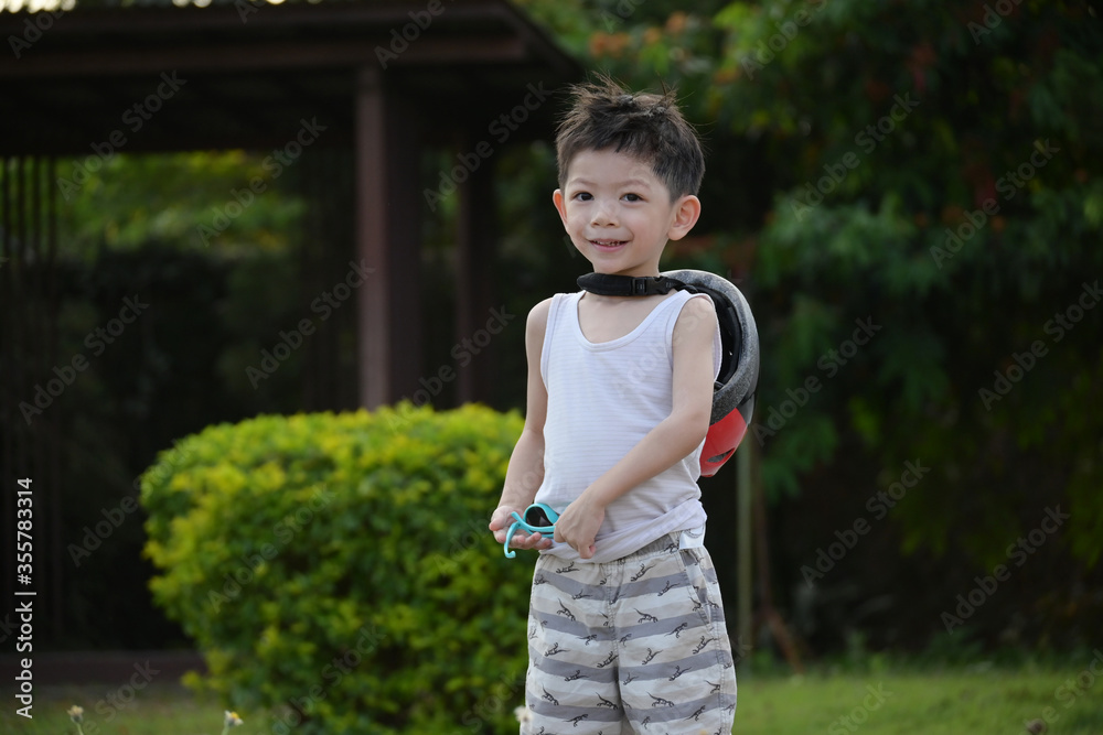 happy cute boy wear sunglasses and sport helmet playing bicycle exercise in the park happy cute boy wear sunglasses and sport helmet playing bicycle exercise in the park
