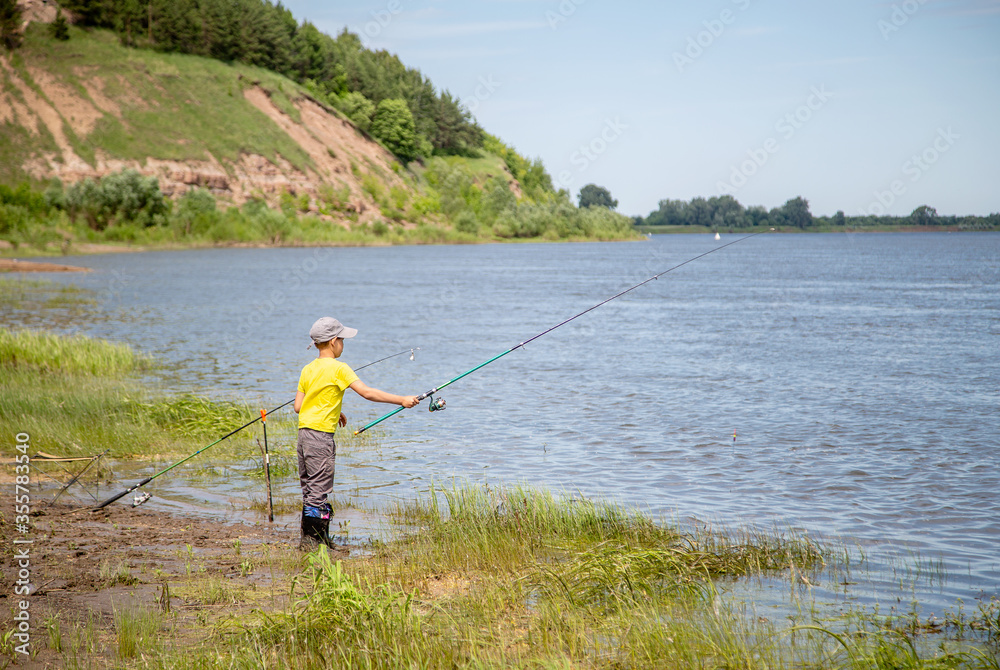 little fisherman in a yellow T-shirt on the shore fishing little fisherman in a yellow T-shirt on the shore fishing