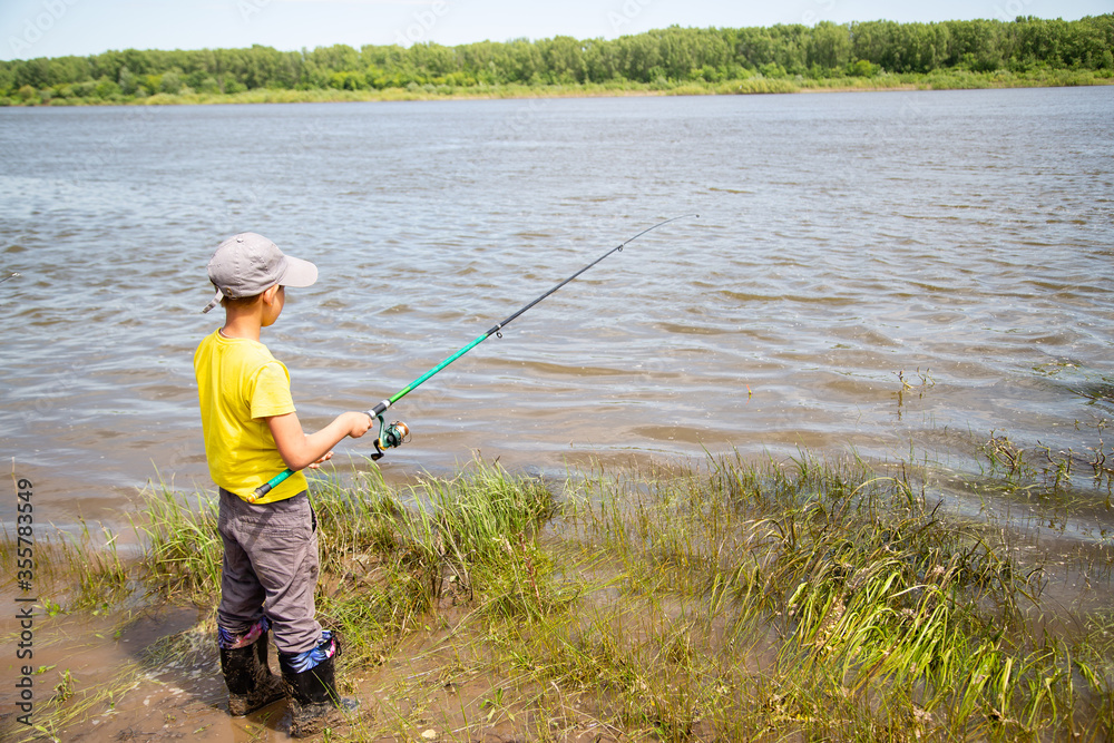 little fisherman in a yellow T-shirt on the shore fishing little fisherman in a yellow T-shirt on the shore fishing