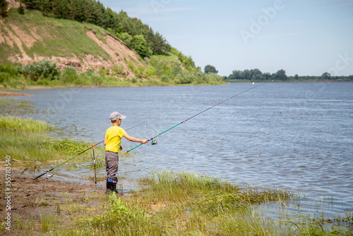 little fisherman in a yellow T-shirt on the shore fishing