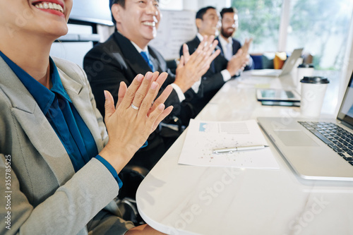 Cropped image of happy business people applauding to speaker at meeting