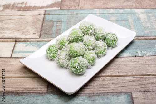 Traditional Malaysian,Indoensian and Singaporean cuisine known as Buah Melaka or Ondeh-ondeh,isolated over wooden background photo