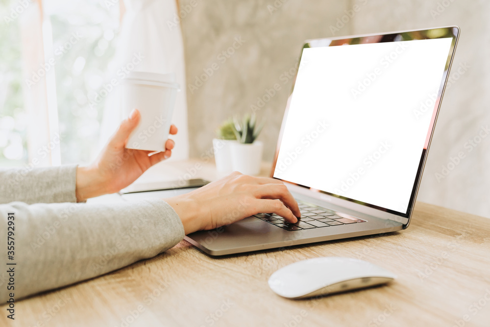 Naklejka premium woman using laptop and holding coffee working on wooden table