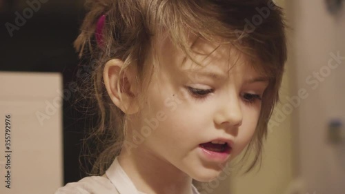 Charming little girl making biscuits at the kitchen table