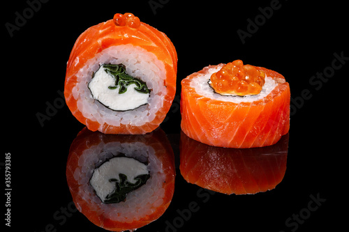Sushi and rolls on a black mirrored background.