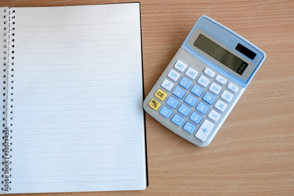 Stationary and blank books on the table, pencil set ,cup of coffee and calculator on wood table , copy space of stationary , working space, space work from home