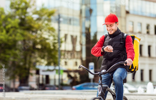 Courier On Bike Checking Time Delivering Food In City