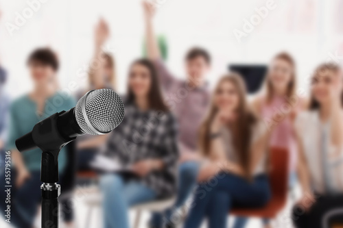 Quadro em tela Modern microphone and people at business training indoors, closeup