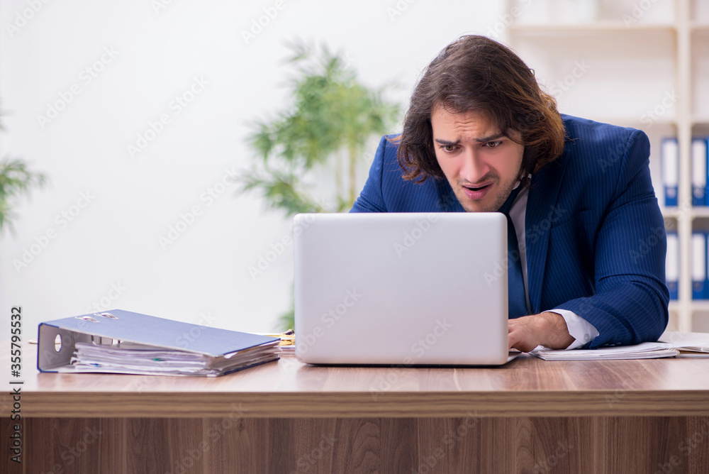 Young male employee unhappy with excessive work Young male employee unhappy with excessive work