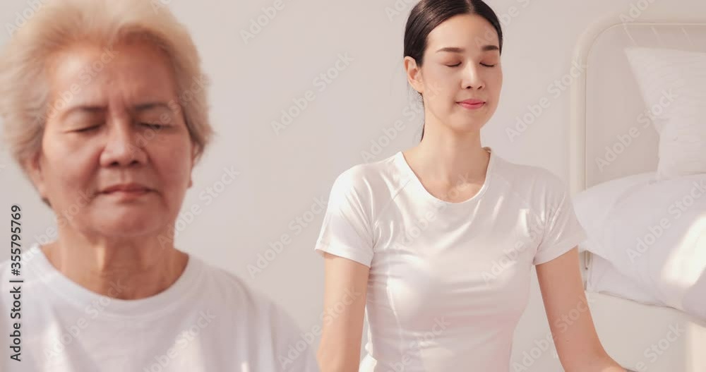 Beautiful woman doing yoga with her mother at home. Relaxed young woman in sportswear is meditating in yoga mat with closed eyes at home. Beautiful woman doing yoga with her mother at home. Relaxed young woman in sportswear is meditating in yoga mat with closed eyes at home.