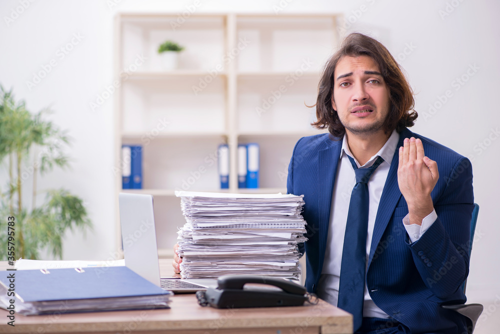 Young male employee unhappy with excessive work Young male employee unhappy with excessive work