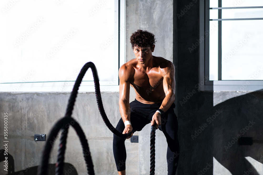 Fitness and sports man training with battle rope in cross fit gym. Fitness Healthy lifestye and workout at gym concept.