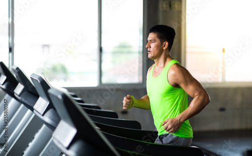 Man running on treadmill machine at gym sports club. Fitness Healthy lifestye and workout at gym concept.