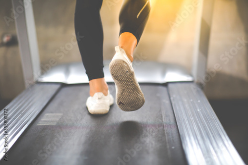 Man running on treadmill  machine at gym sports club. Fitness Healthy lifestye and workout at gym concept. Selective focus at mele shoe. photo
