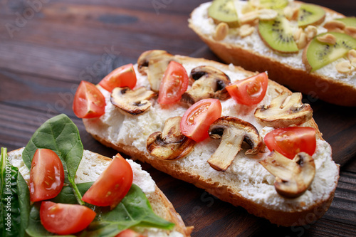 Assorted bruschettas with various toppings. Appetizing healthy homemade snacks, vegetarian toasts with fruits, vegetables and mushrooms. Balanced food, Italian antipasti variation