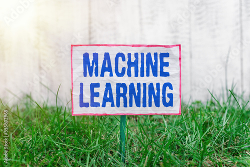 Text sign showing Machine Learning. Business photo text the concept that a computer can learn new data itself Crumpled paper attached to a stick and placed in the green grassy land photo