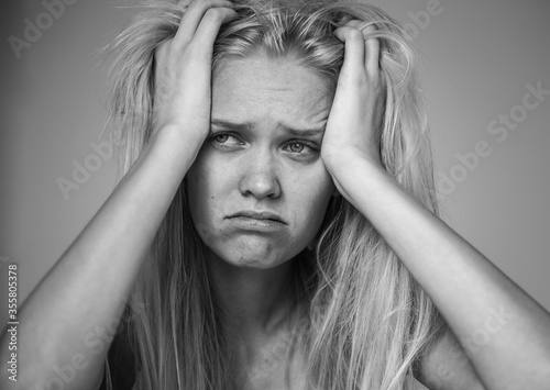 Closeup of sad girl with her hands up in her hair.. Black and white isolated portrait.