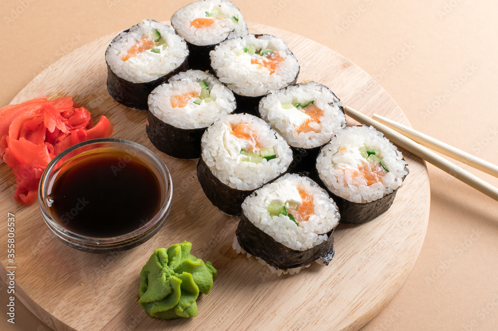 Sushi rolls set served on wooden board. Beige background Sushi rolls set served on wooden board. Beige background