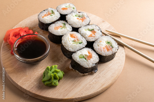 Sushi rolls set served on wooden board. Beige background