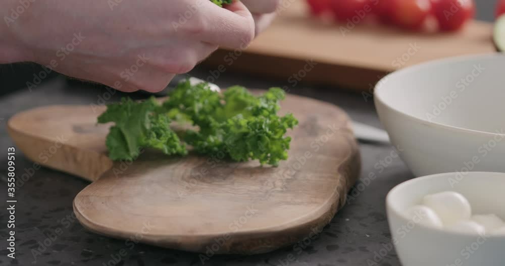 Slow motion man massaging kale leaves to make it softer for salad on kitchen side view