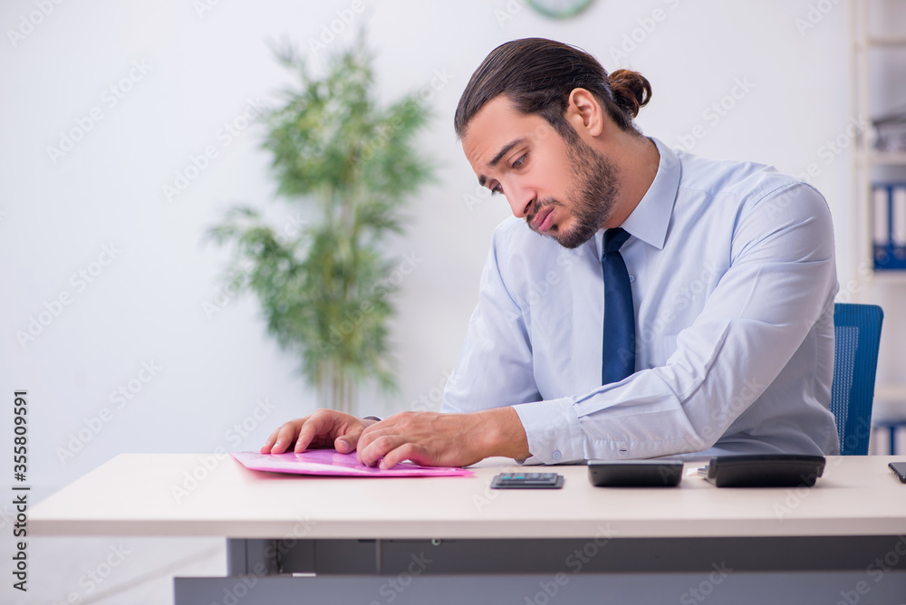 Young male employee in budget planning concept Young male employee in budget planning concept