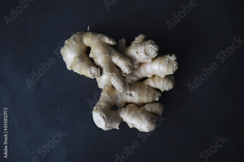 Ginger root whole and sliced. Ginger tea with lemon on the dark background. Fresh ginger root on stone background. Vitamins. Free space for your text.