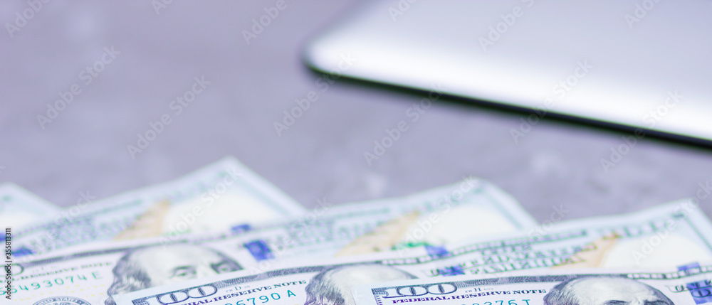 One hundred dollars. American currency. Tablet and hundred dollar bills on a gray background. Financial investment. Copy space One hundred dollars. American currency. Tablet and hundred dollar bills on a gray background. Financial investment. Copy space