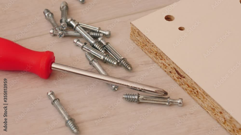 Assembling furniture at home. Many mounting screws with screwdriver and board on floor.  Do it yourself furniture assembly