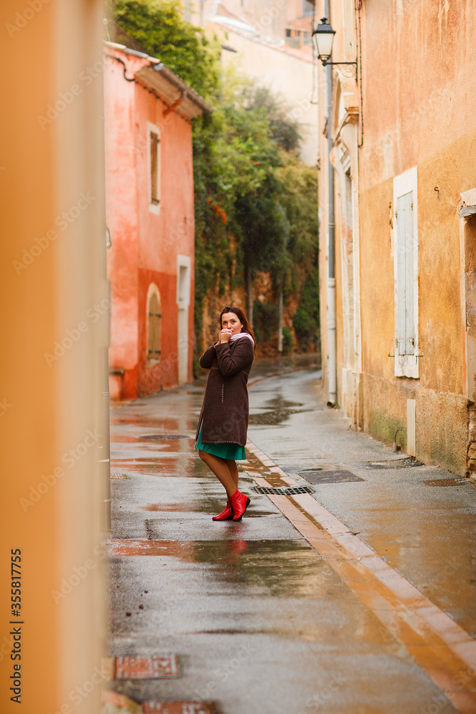 girl walks in rain on street of small town in Provence France. a trip to Europe.