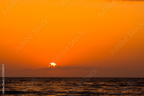 Amazing sea sunset on the pebble beach  the sun  waves  clouds