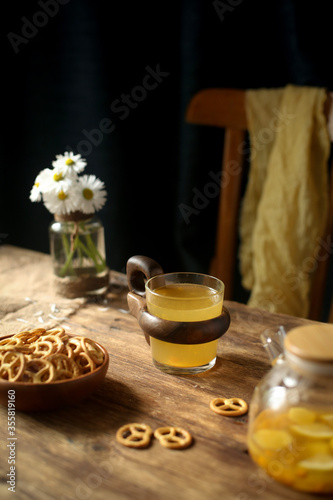 Cookies, fruit tea on a wooden table, a chair in the background.
