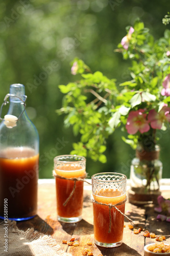 Near the window on a wooden table is a bottle with kvass and two glasses
