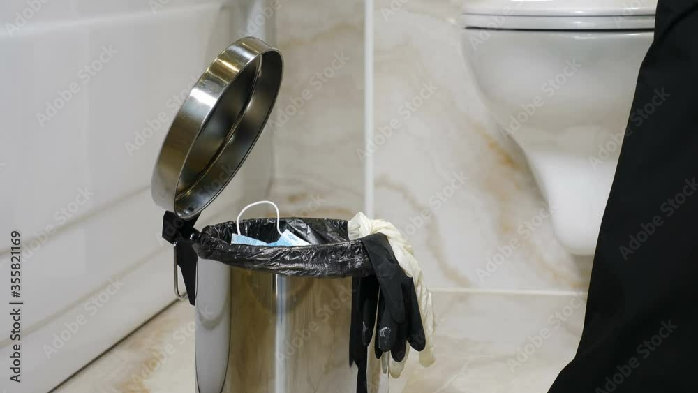 End of Covid-19 corona virus and pandemic. Throwing used facemask madical disposable item into bin. Utilization of protective things. Quarantine time finishing. Used face masks and gloves throwaway in