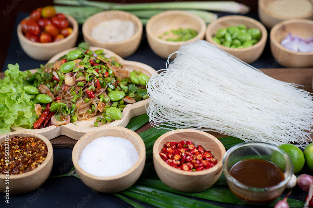 Raw rice flour in a wooden bowl with spices On a dark wood with natural light, focusing on the top of the noodles