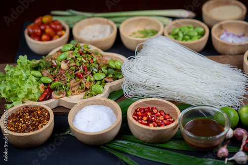 Raw rice flour in a wooden bowl with spices On a dark wood with natural light  focusing on the top of the noodles