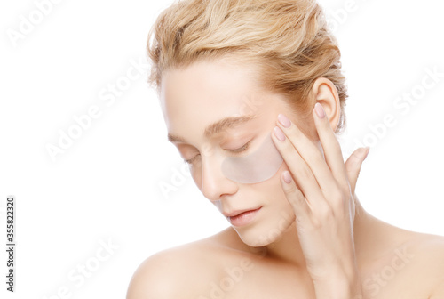 Fotografia Beautiful woman holding collagen eye patch with one hand, isolated on white background