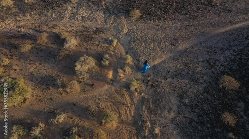 Aerial view of woman in a beautiful blue dress walking throuht the nature reserve at sunset. Meditative and breathing practices. Tenerife, Canary Islands, Spain photo