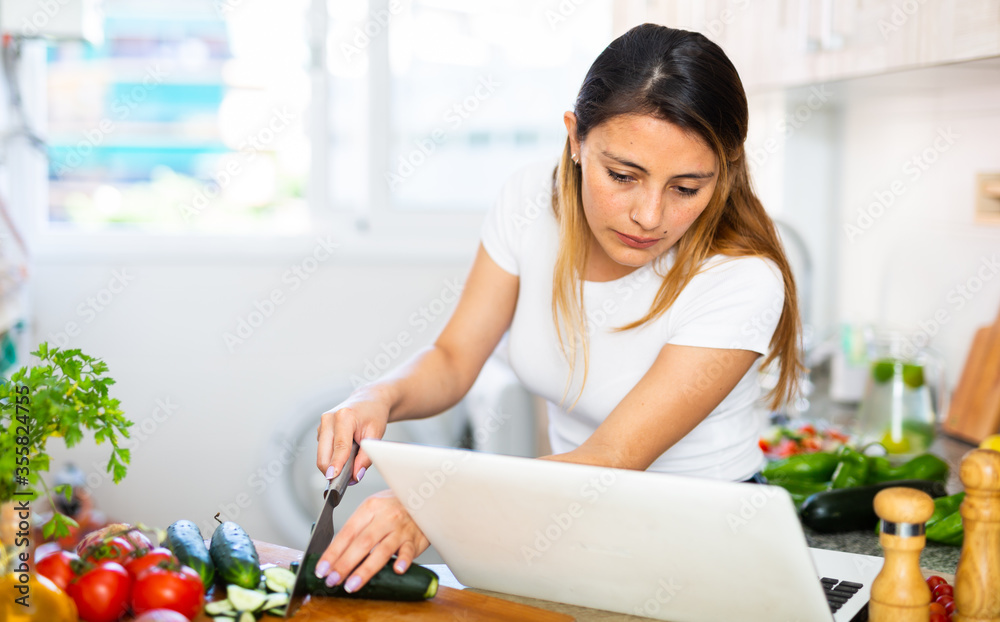 Nice latino woman planning to cook, looking for recipe on internet