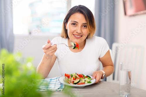 Mexican housewoman eating vegetable salad from plate photo