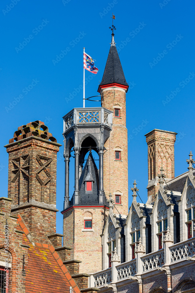 Obraz premium Stepped gable, tower and tall brick chimney on the roofs of houses in Bruges