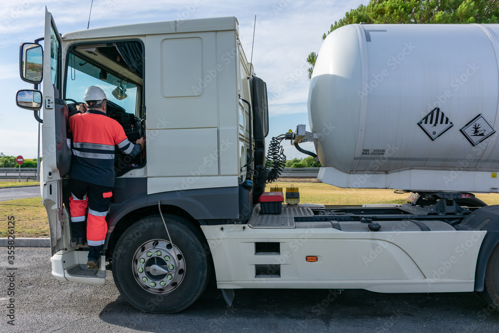 Dangerous goods tank truck driver getting into the cab using the two handles safely