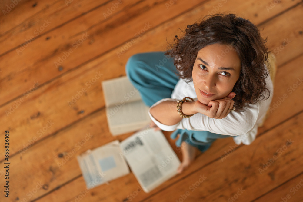 A curly-haired girl with books is sitting on the wooden floor. Distance learning A curly-haired girl with books is sitting on the wooden floor. Distance learning