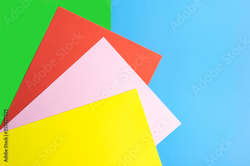 Color papers geometry flat composition background with yellow, red, pink and green tones on a blue background. 