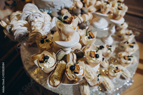 Wedding decoration with colorful cupcakes, eclairs, meringues, muffins cookies.